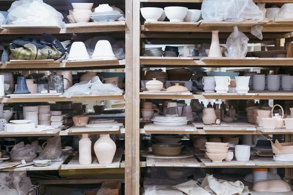 Bisque-fired cups and bowls on a wooden shelf