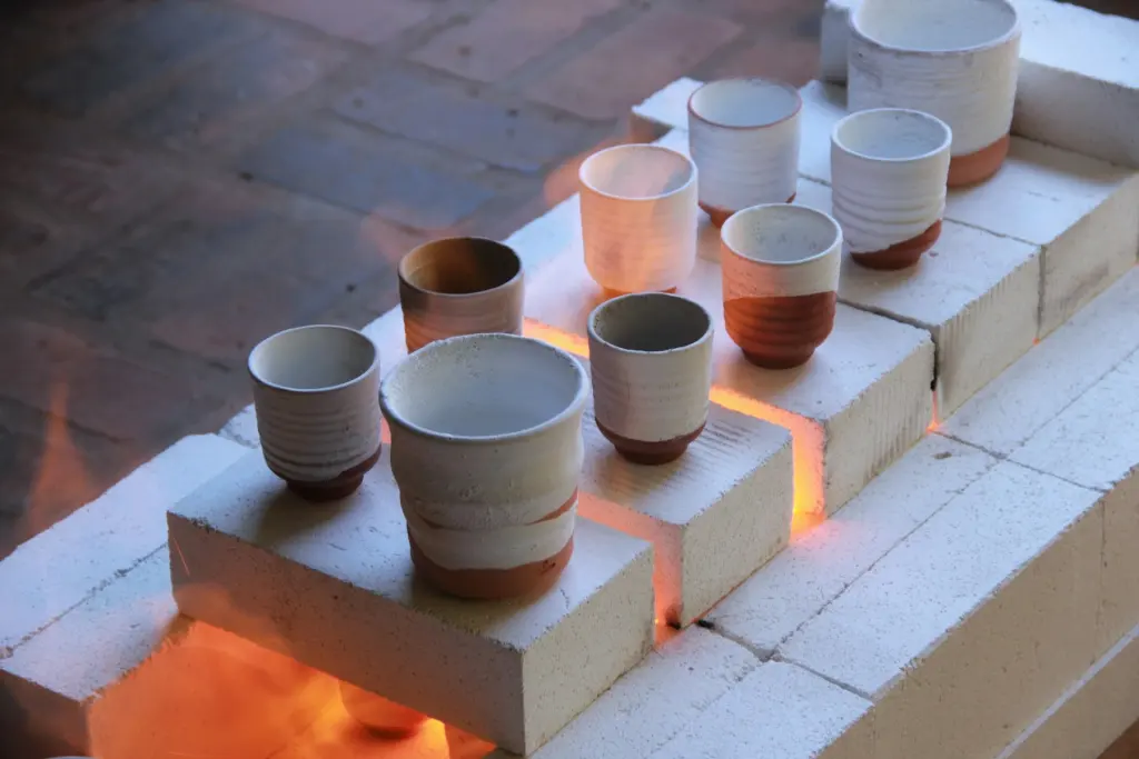 Glazed cups glowing on kiln bricks after firing