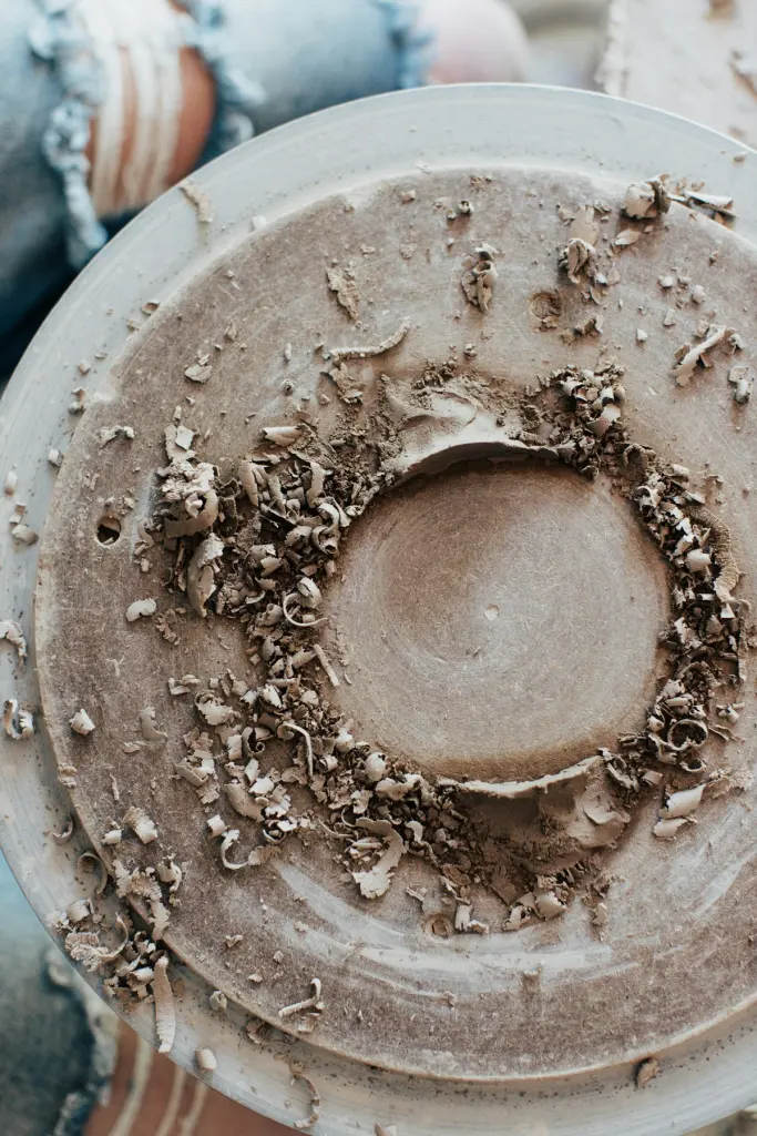 Clay trimmings around a pot being trimmed on the wheel
